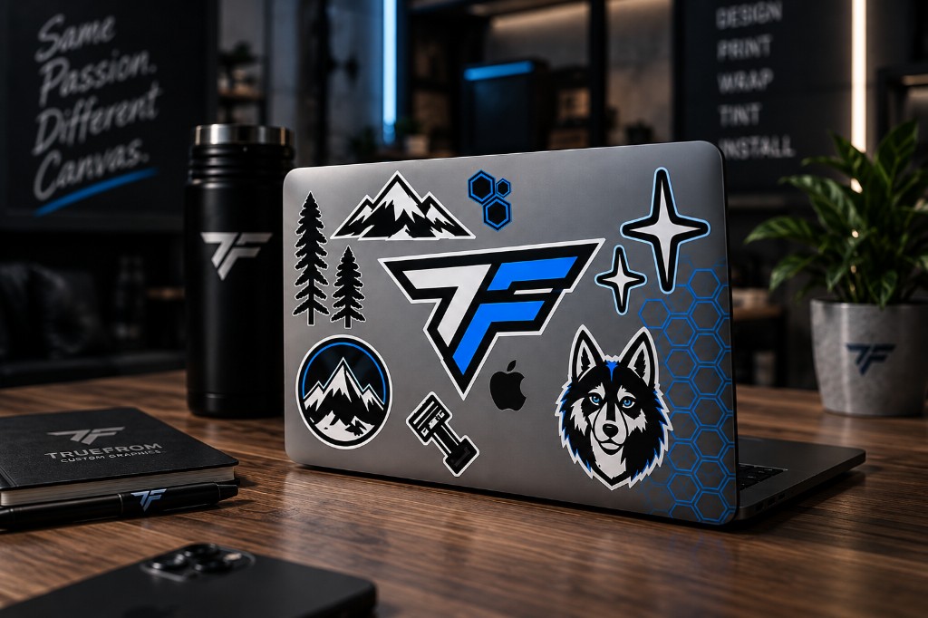 Laptop, bottle, and notebook with TRUEFORM vinyl stickers